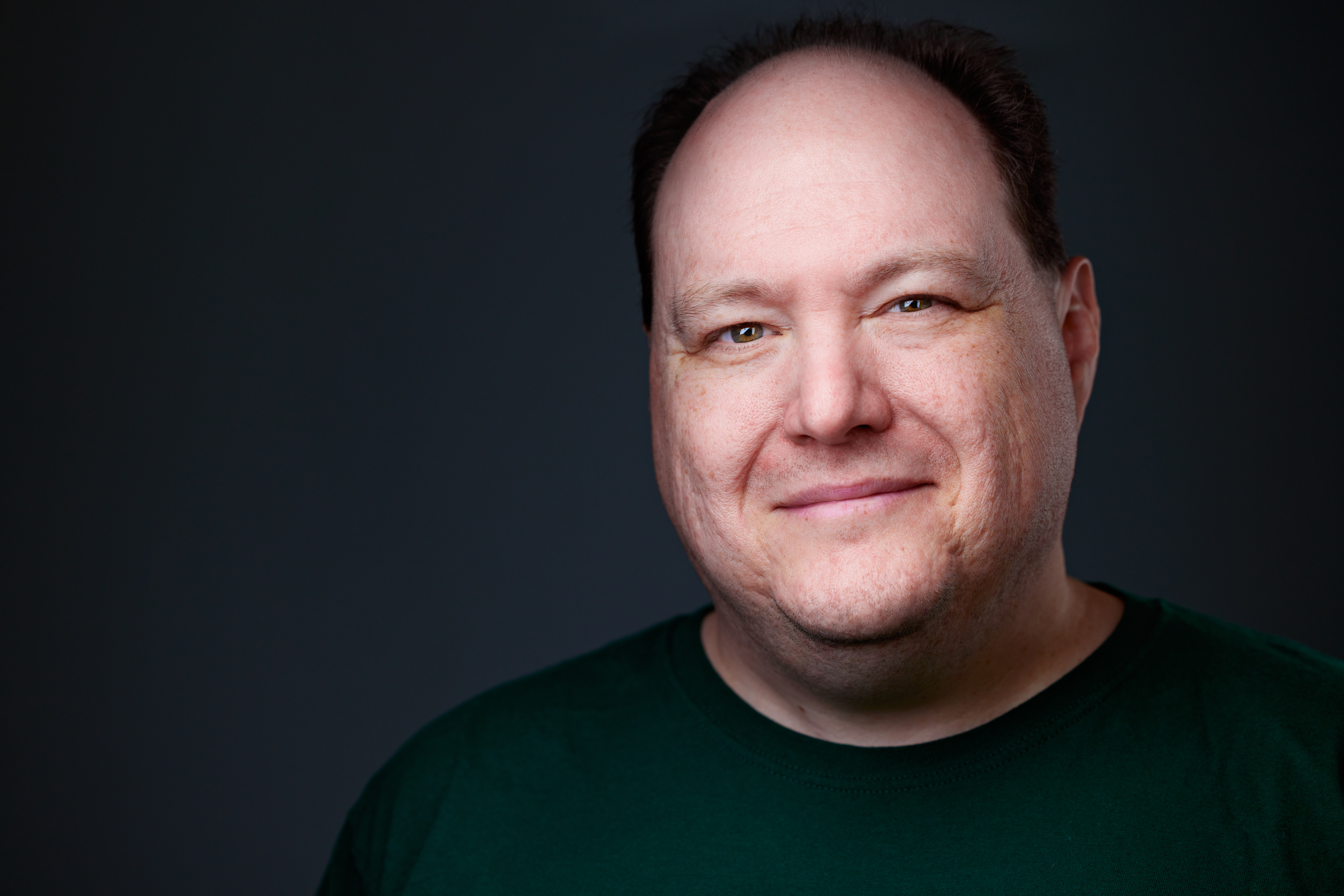 The author's headshot; looking at the camera, faint half-smirk, receding hairline, brown hair green eyes.